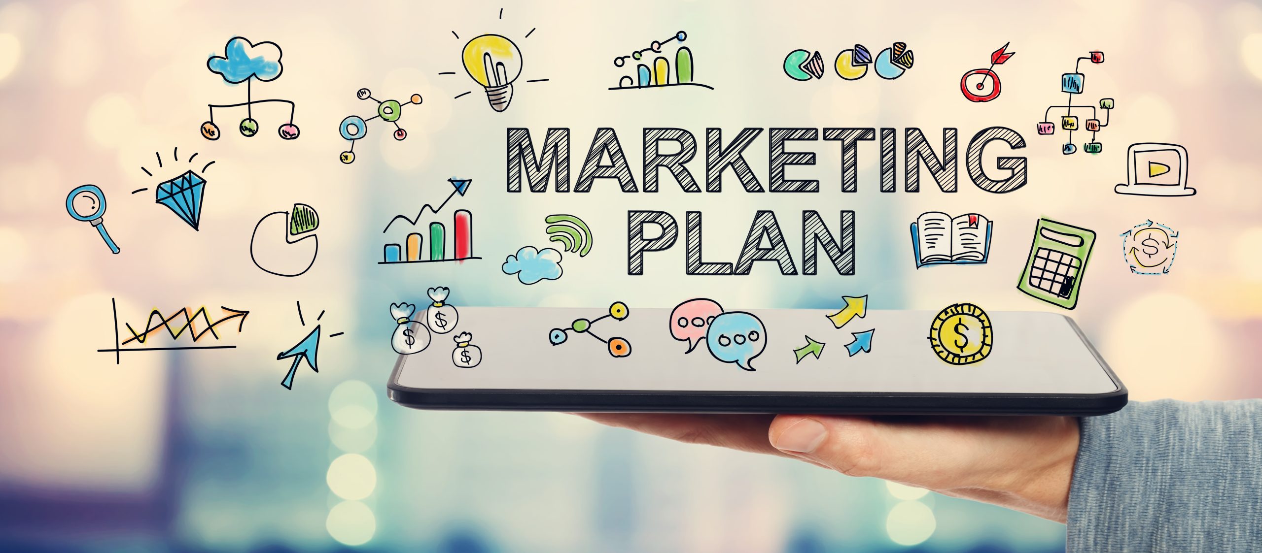 Tablet showing the words 'MARKETING PLAN' with colorful surrounding doodles of charts, graphs, money symbols, a lightbulb, book and arrows, illustrating planning concepts.